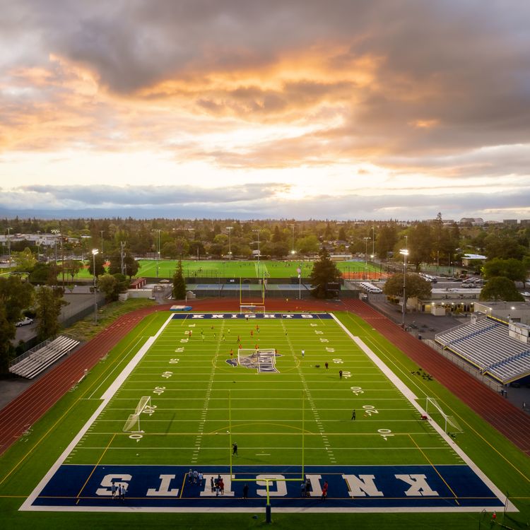 An American football field beneath a dramatic evening sky